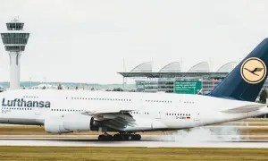Lufthansa-Flugzeug landet auf dem Rollfeld, Rauch steigt auf.