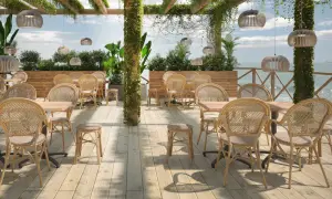 Terrasse mit Rattanmöbeln und Blick aufs Meer.